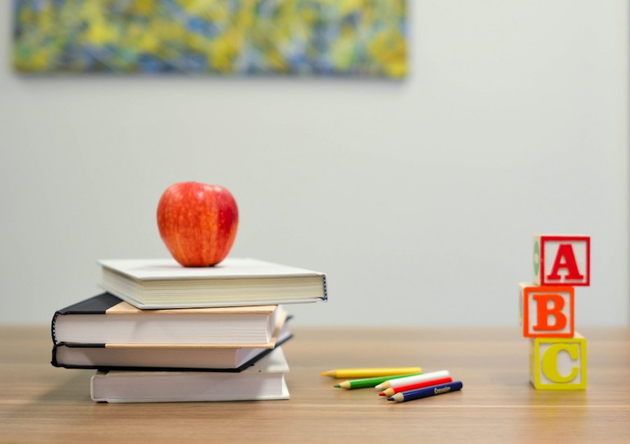An apple resting on a stack of books beside colored letter blocks