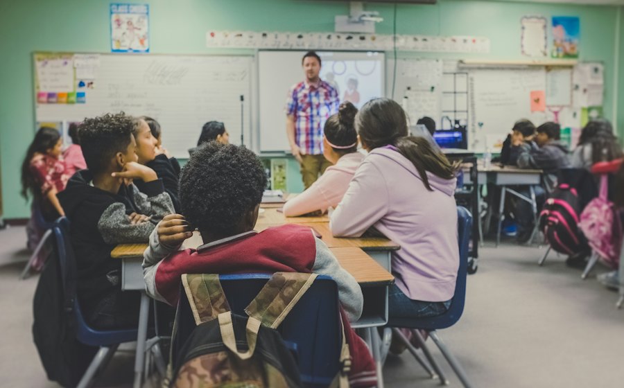 A classroom with students at tables and a teacher at the board