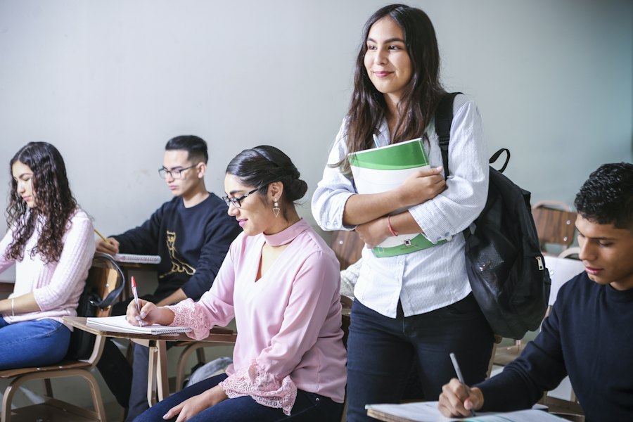 Smiling students sitting together in a classroom with books and notebooks
