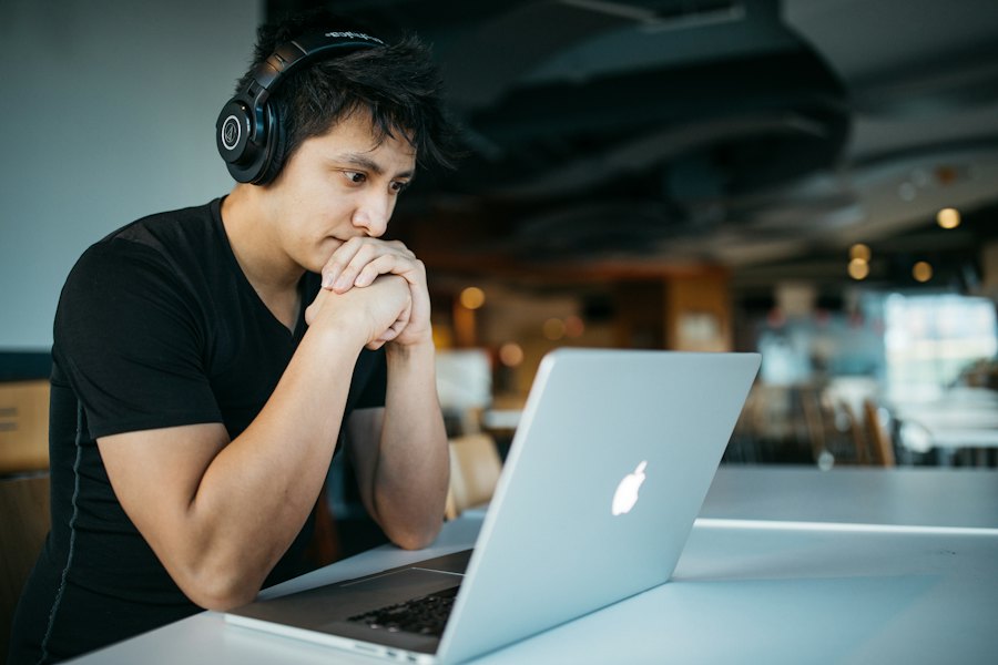 A student wearing headphones and studying on a laptop