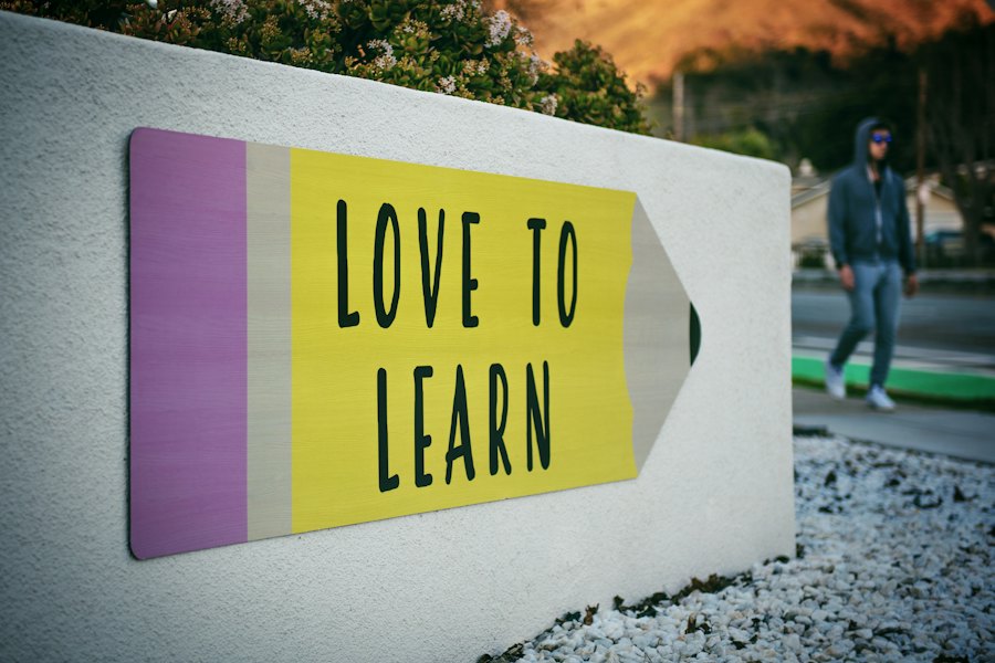 A painted pencil sign that reads Love to Learn